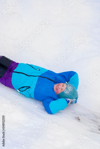 happy boy riding down an ice slide in winter outside