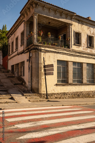 A rustic building on a street in the small town of Bejar in the mountains of north Spain. The building is situated on a road next to a crossing and has a balcony  photo