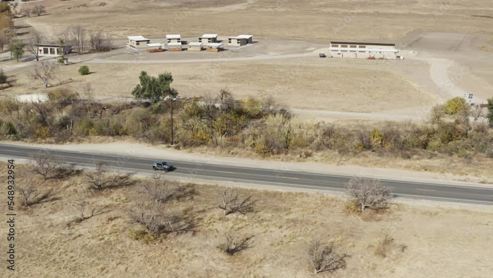 Drone shot of road in the countryside with wide meadow, seen cars passing Drone shot of road in the countryside with wide meadow, seen cars passing