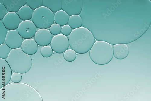 Oil and water bubbles of different sizes air bubble an attractive pattern with blue-green gradient lighting effect to create an art image background.