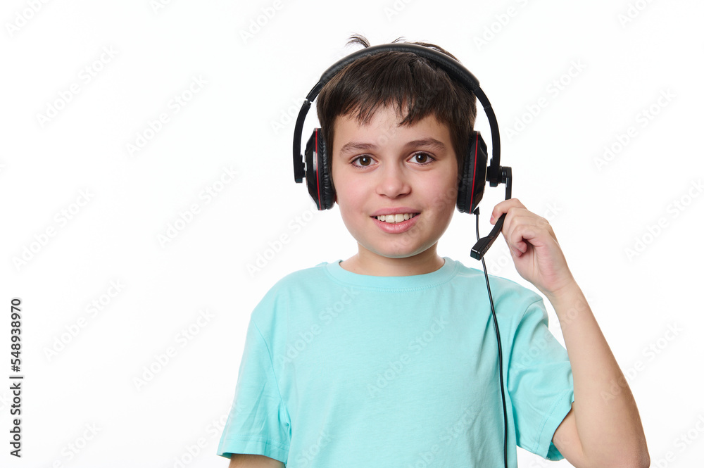 Isolated portrait on white background of a handsome dark-haired multi-ethnic child boy, wearing audio headset during a video class, smiling looking at camera. Children and technology. Online education Isolated portrait on white background of a handsome dark-haired multi-ethnic child boy, wearing audio headset during a video class, smiling looking at camera. Children and technology. Online education
