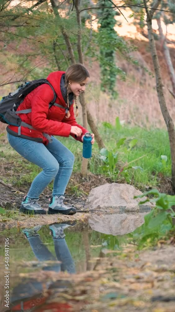 Young female trekker filling water bottle of raw water in a river. Young female trekker filling water bottle of raw water in a river.