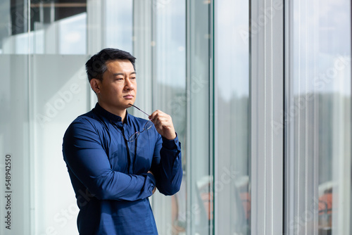 Slika na platnu Successful Asian businessman thinking by the window, man in shirt and glasses investor thinking about future plans