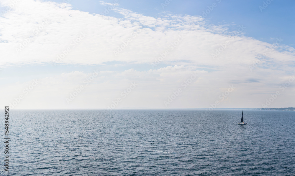 Segelboot auf offener See. Panorama über Ocean mit einsamen Segelboot am Horizont.
Sailboat on the open sea. Panorama over ocean with lone sailboat on horizon.