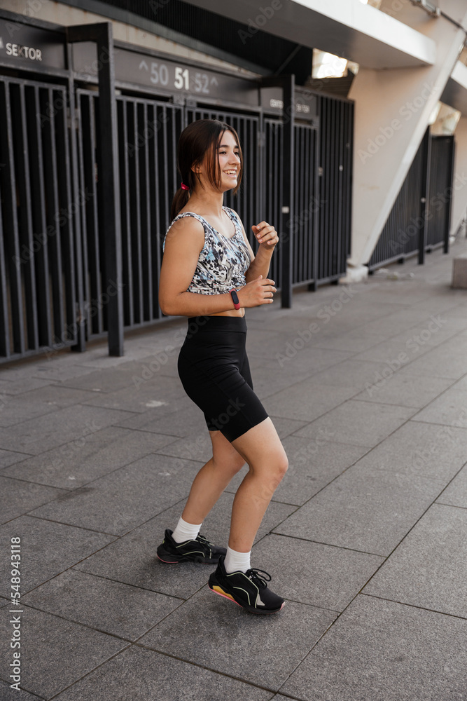 Teenage girl doing sports warm-up and wrestling exercises on the street against the city background Teenage girl doing sports warm-up and wrestling exercises on the street against the city background