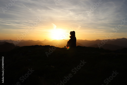 young woman is sitting on a mountain during sunrise 