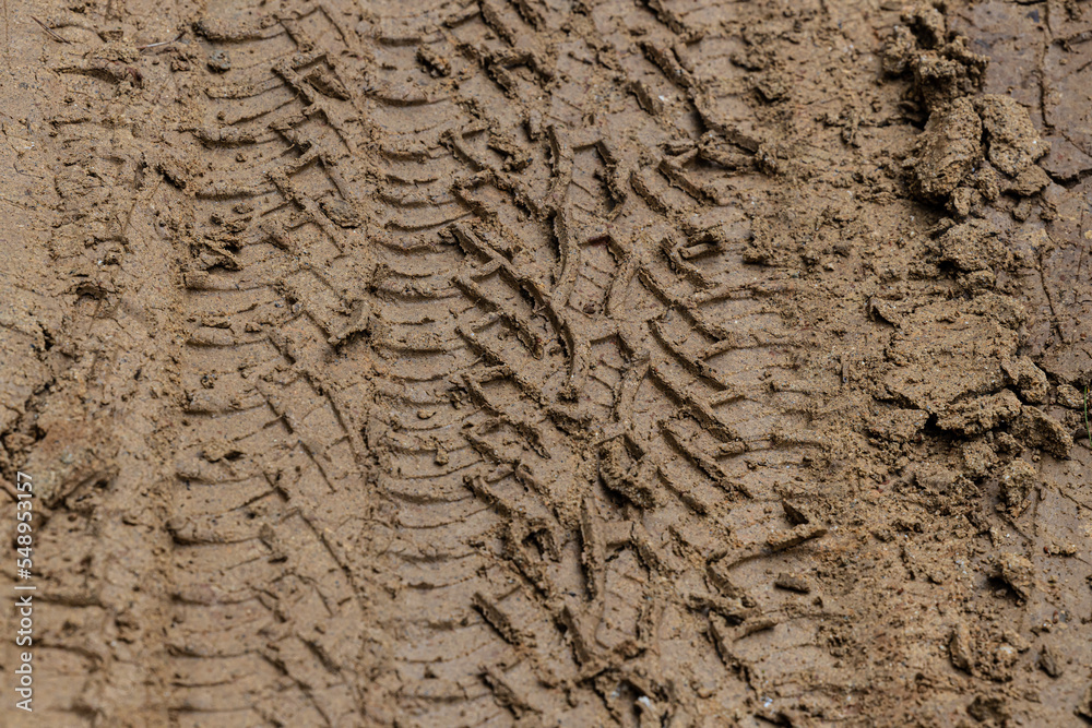 Tire tracks from the wheels of passing cars in the wet, softened ground on a muddy rural road.Multi layers of tire tracks print on dirty brown soil.Wheel marks of cars and trucks on countryside route. Tire tracks from the wheels of passing cars in the wet, softened ground on a muddy rural road.Multi layers of tire tracks print on dirty brown soil.Wheel marks of cars and trucks on countryside route.