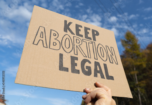 Female hand holding sign with slogan Keep Abortion Legal. Woman with placard supporting abortion rights at protest rally demonstration. photo