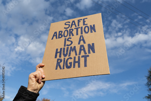 Woman holding sign with slogan Safe abortion is a human right. Female protester with placard supporting abortion rights at protest rally demonstration.