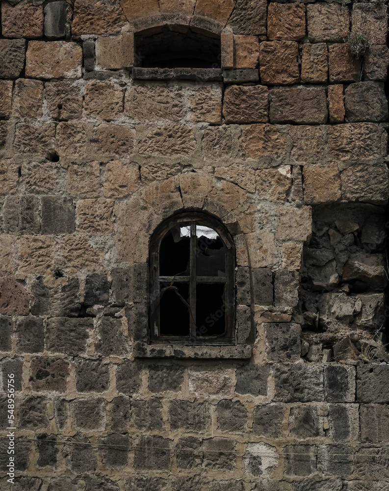 architecture background of stone grey wall one Window in a medieval building. front view. brick wall with a old window frame. Stone wall of an old building with two arched windows. Windows are closed
