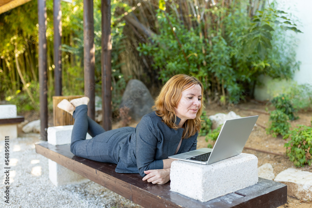 A beautiful freelancer woman works at the park using a computer.