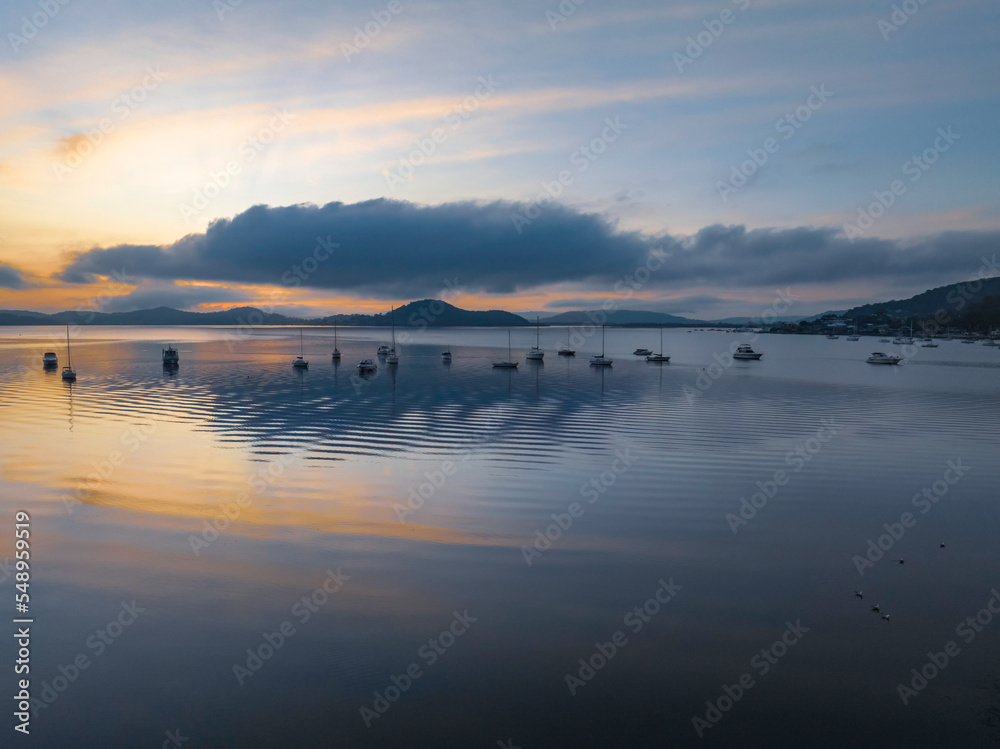 Fototapeta premium Sunrise over the water with fog, boats, clouds and reflections