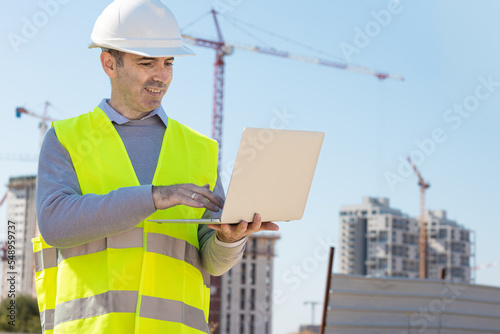 Professional builder standing with notebook in front of the construction site