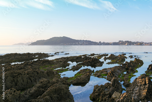 Coastal rock pools and distant view of town, Rias Baixas, Panxon, Nigran, Galicia, Spain photo