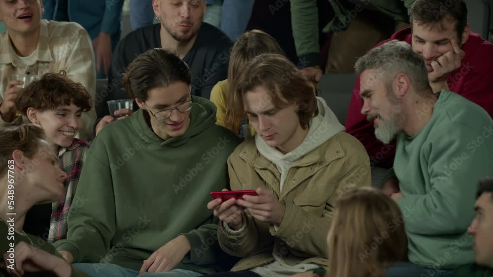 Audience sits at sports event, looking into the phone screen of a spectator instead of the game Audience sits at sports event, looking into the phone screen of a spectator instead of the game