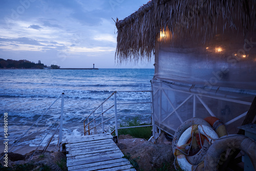 Obraz na plátně fisherman's hut at sunrise on the sea coast with lighthouse on a horizon