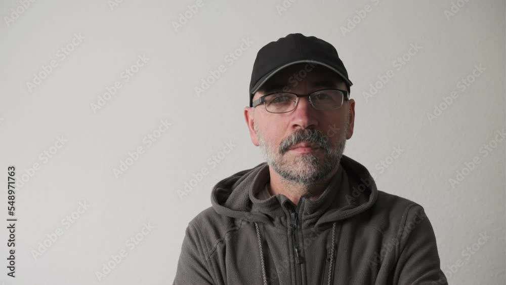 Bearded man in a cap and glasses on a white background in the studio looking at the camera and smiles. Bearded man in a cap and glasses on a white background in the studio looking at the camera and smiles.