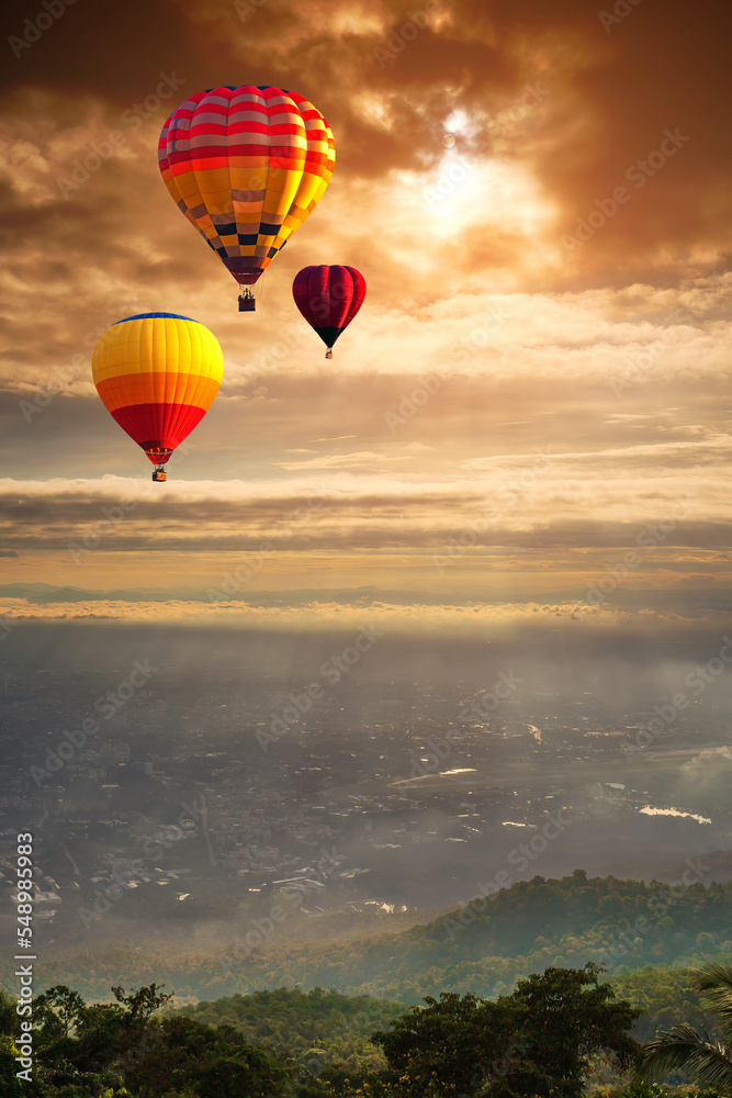 Naklejka premium Colorful balloons floating over big city and mountain, sunset background. Hot air balloon over Chiang Mai City in Thailand. aviation and doi suthep.