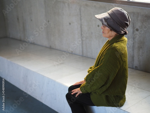 屋内のベンチで座る高齢日本人女性の横顔