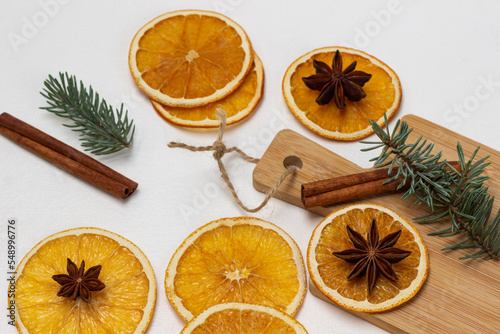Star anise on dry orange slices, cinnamon and sprig of spruce on board and on the table.