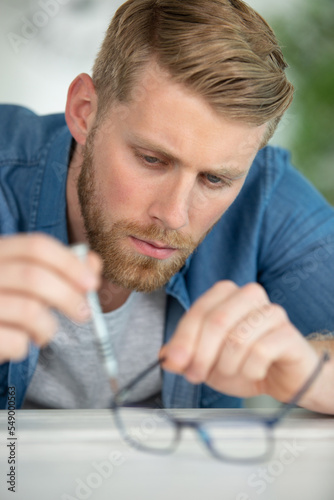 optician repairing and fixing eye glasses photo