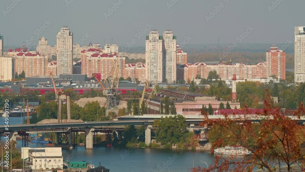 Panoramic top view of Kyiv city over Dnipro river, skyscrapers, bridge with cars, residential buildings and plants, autumn landscape. Tranquill peaceful background, haze over city. High quality 4K Panoramic top view of Kyiv city over Dnipro river, skyscrapers, bridge with cars, residential buildings and plants, autumn landscape. Tranquill peaceful background, haze over city. High quality 4K