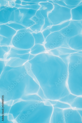 Background, blue water waves in the pool with sun reflection. Top view, selective focus