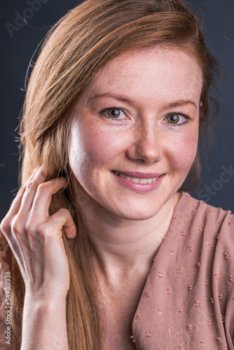 Portrait of a young red-haired woman in a dark studio
