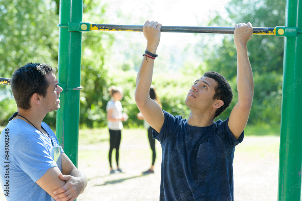 young man exercising on monkey bars in the park