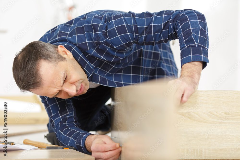 man is fixing the dresser panel with nails man is fixing the dresser panel with nails