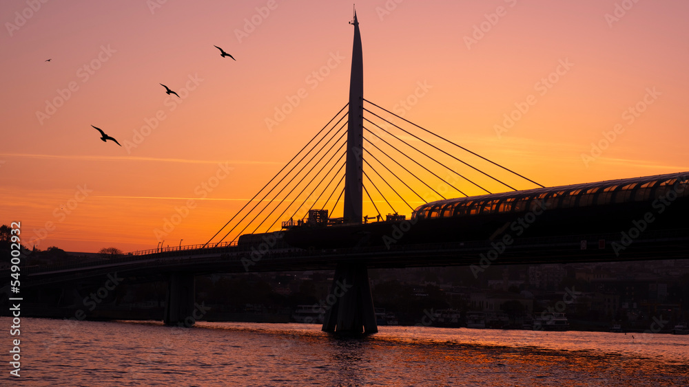 Obraz premium Beautiful sunset, Golden hours, Golden Horn metro bridge and the view of the Golden Horn in Istanbul, the sunset, the birds heading towards the sun, The image with space and text area.