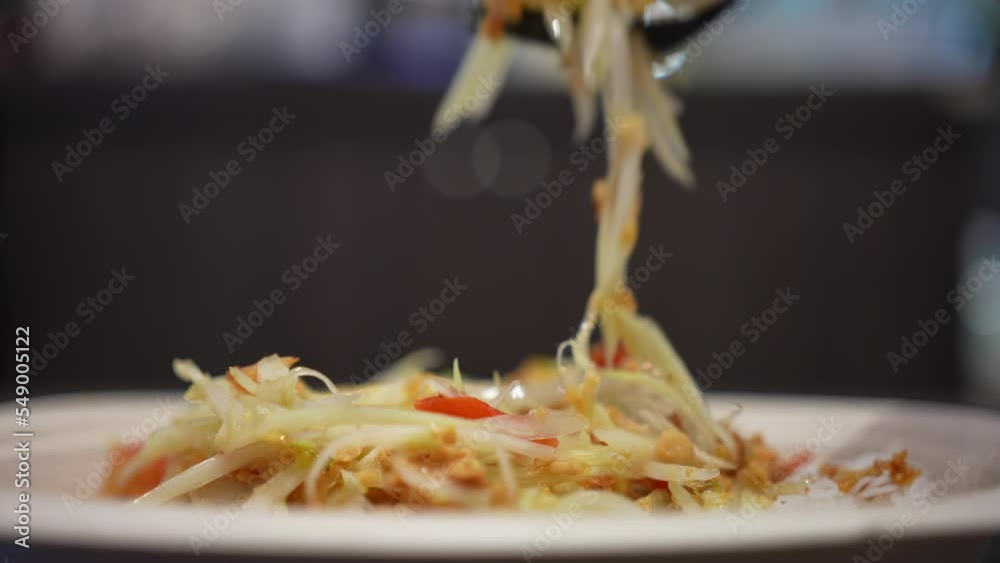 Close up of hand eats papaya salad, som tum, tum Thai, asia salad made of papaya and vegetables Thai Style served in the restaurant.