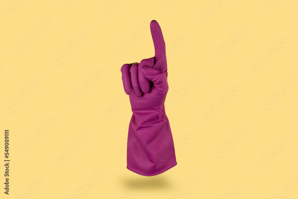 Purple cleaning glove floating in the air on yellow background counting one with finger Purple cleaning glove floating in the air on yellow background counting one with finger