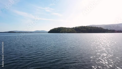 Low fly along loch Lomond water and lift up to reveal island on a sunny day photo