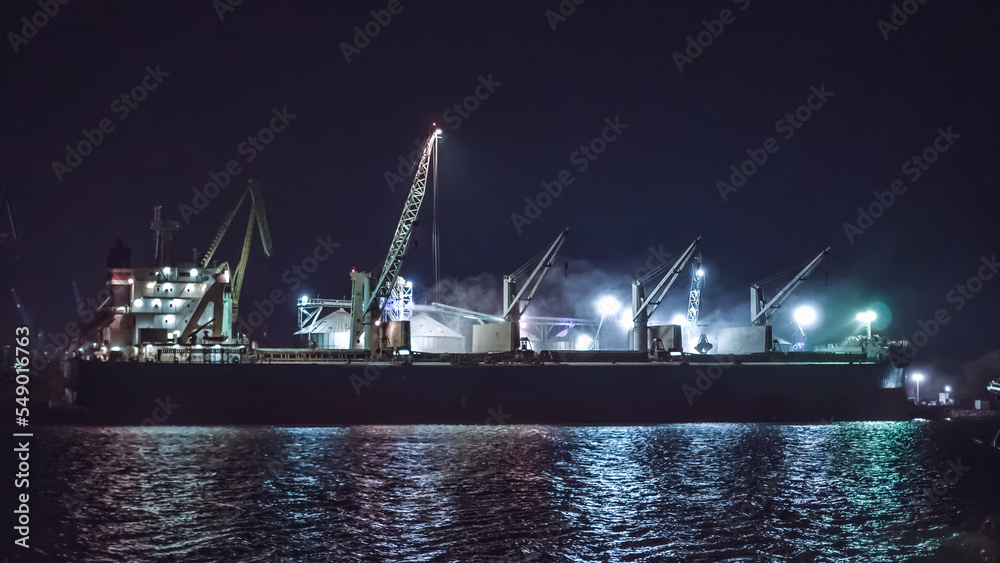 Obraz premium Black Sea grain export deal. Loading grain cargo vessel with grab late at night