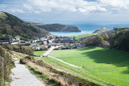 Stone road from Durdle door to Lulworth cove, part of Jurassic Coast World Heritage Site, view of the seaside cottages and Lulworth Cove in the background, selective focus