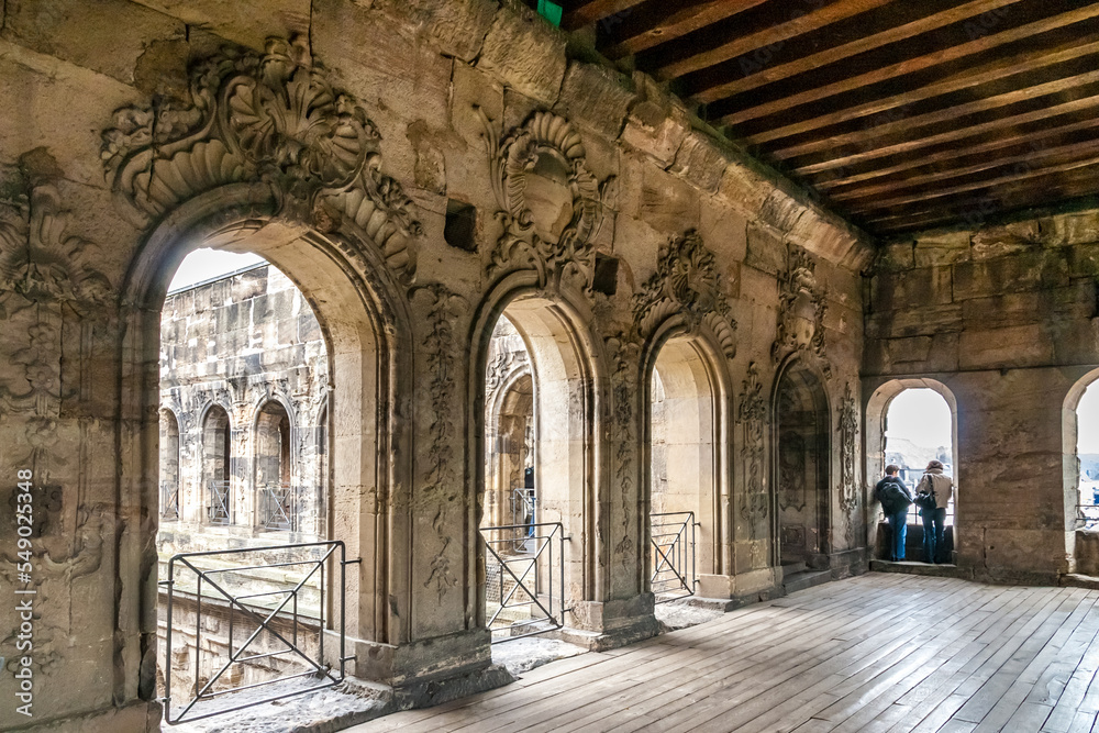 Nice view inside a room with a wooden floor, wooden beam ceiling and Baroque reliefs carved out of the sandstone wall of the famous Porta Nigra, a large Roman city gate in Trier, Germany. 