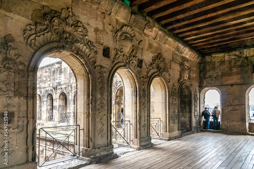 Nice view inside a room with a wooden floor  wooden beam ceiling and Baroque reliefs carved out of the sandstone wall of the famous Porta Nigra  a large Roman city gate in Trier  Germany. 
