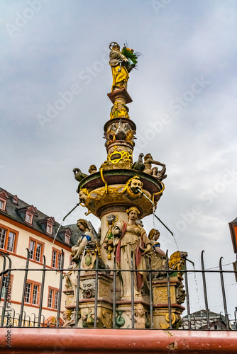 Close-up view of the fountain Petrusbrunnen in the central square called Hauptmarkt on a cloudy day in Trier, Germany. On top of the fountain column stands a figure of Saint Peter, the city's patron. photo