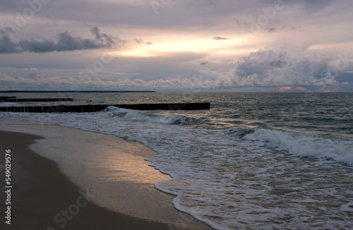 View to wonderful landscape on Baltic Sea with sea waves  piers and beautiful heavy colorful clouds on skyline on colorful sunset