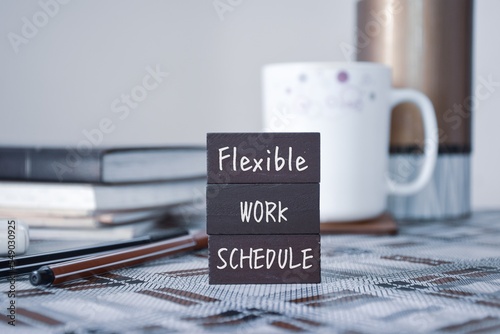 Wooden chips with the inscription Flexible Work Schedule on workplace background.  photo