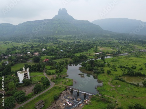 Aerial view of the river and greenery before the silhouettes of Malang Gad on the mountains photo