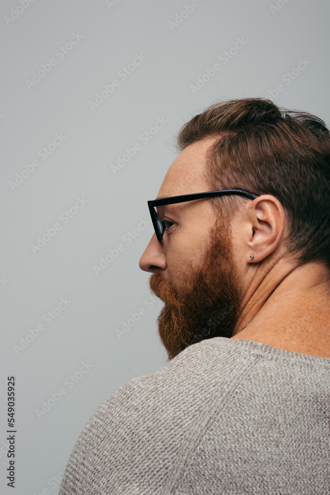 Fototapeta premium Side view of stylish bearded man in eyeglasses looking away isolated on grey.