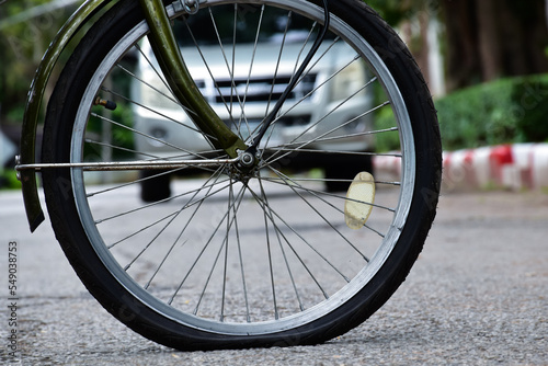 Rear wheel of bike which is flat and parked on the pavement beside the road.	