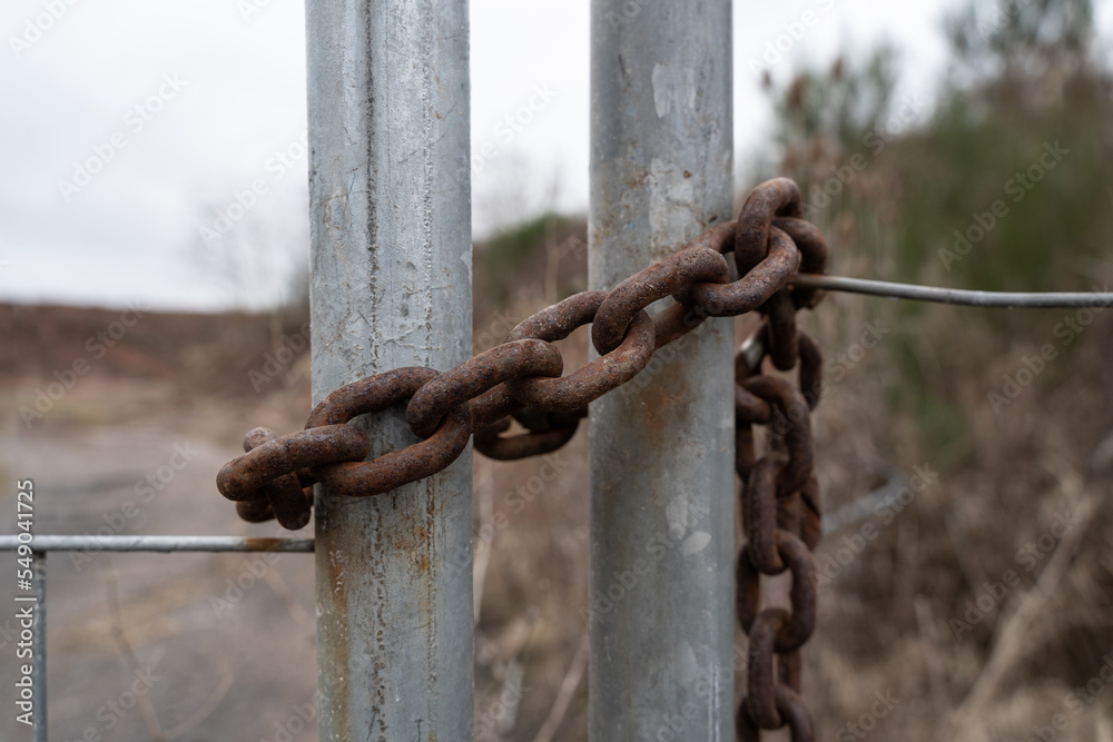 Old rusted iron chain on a metal gate of a property Old rusted iron chain on a metal gate of a property