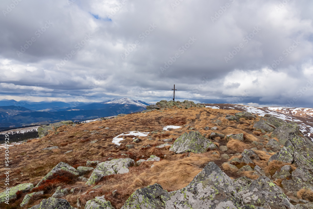 Fototapeta premium Scenic view from summit cross of mountain peak Gertrusk surrounded by alpine meadow, Saualpe, Lavanttal Alps, border Styria Carinthia, Austria, Europe. Hiking trail in Wolfsberg region on cloudy day