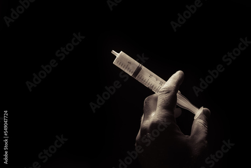 syringe in hand on a dark background