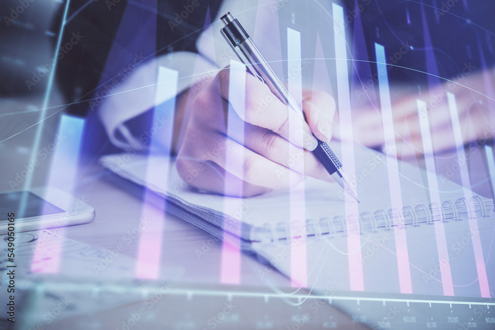 A woman hands writing information about stock market in notepad. Forex chart holograms in front. Concept of research. Multi exposure A woman hands writing information about stock market in notepad. Forex chart holograms in front. Concept of research. Multi exposure