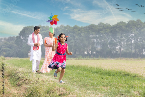 Happy parents with cute little girl running carefree and having fun with colorful pin wheel.