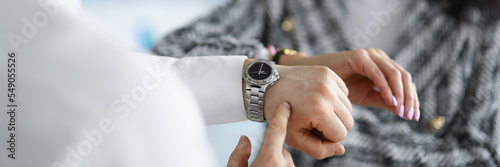 Businesspeople comparing time on wristwatches, coworkers check if time right on dial photo